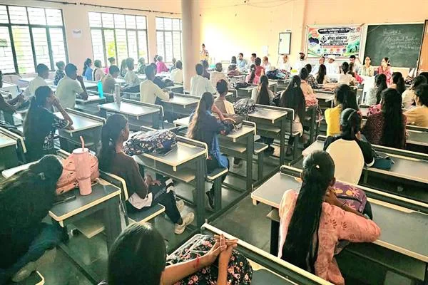 कॉलेज के कक्ष में डेस्क पर बैठे छात्र-छात्राएं और सामने मंच के पास मौजूद शिक्षक व अतिथि