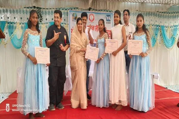 मंच पर हल्के नीले परिधानों में चार बालिकाएं प्रमाणपत्र लिए खड़ी हैं और उनके साथ अन्य अतिथि मौजूद हैं